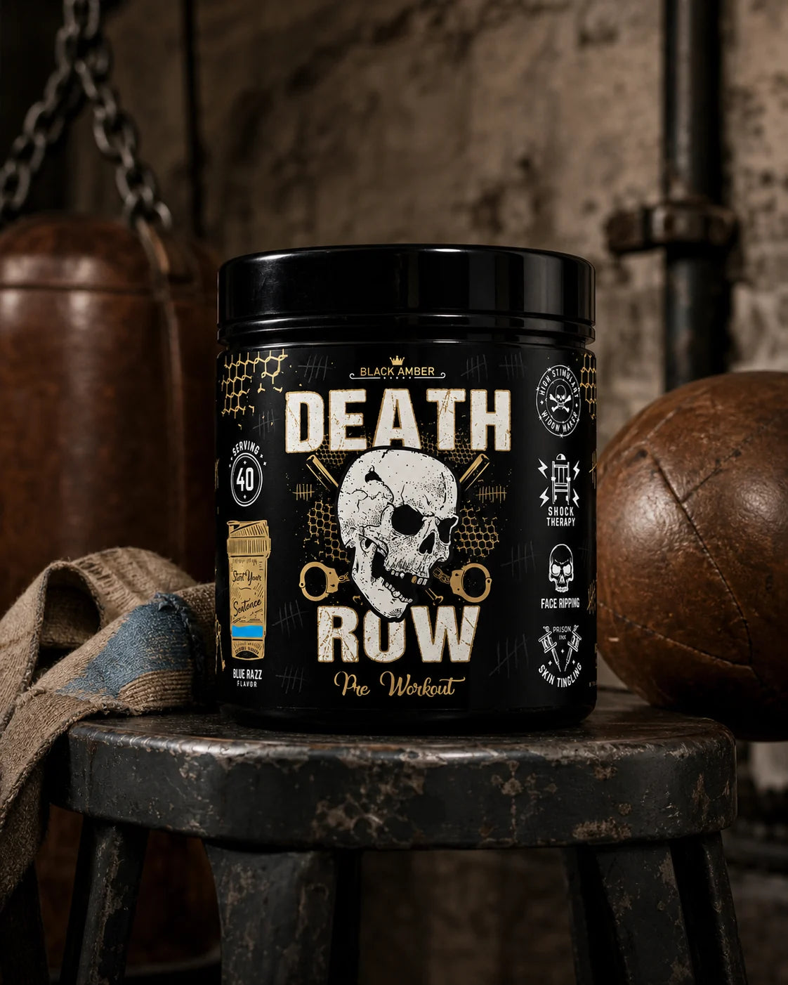 Black Amber Death Row Blue Razz pre-workout tub on a worn boxing stool beside a leather medicine ball and hand wraps