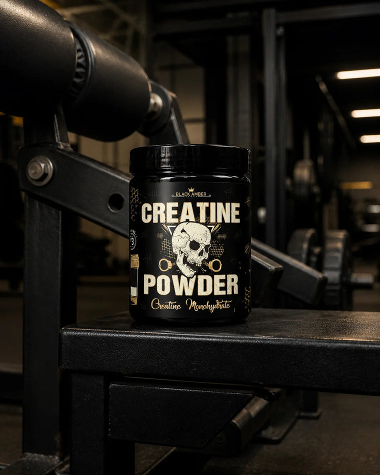 Black Amber Creatine Powder tub on a padded leg-curl machine support in a dark industrial gym