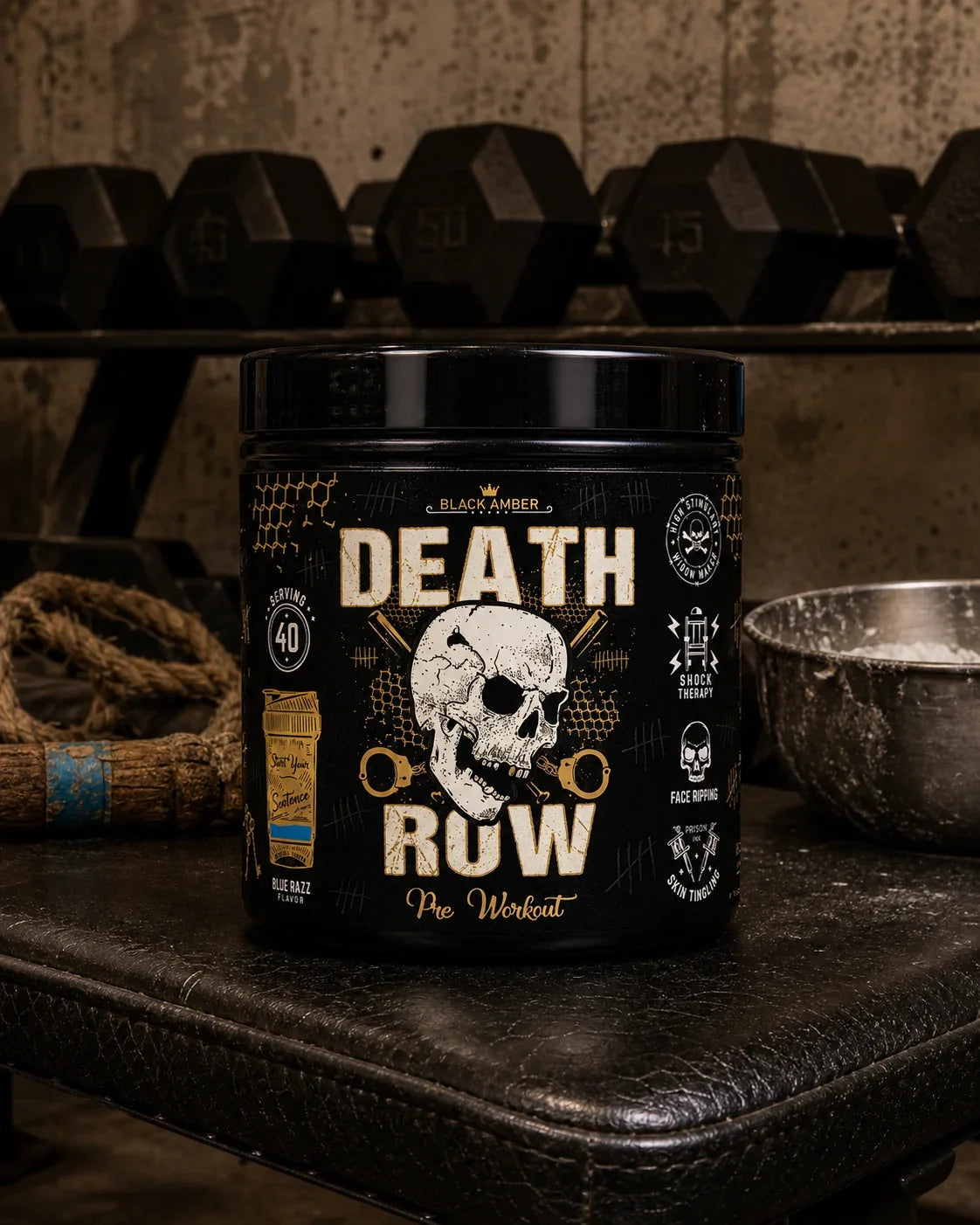 Black Amber Death Row Blue Razz pre-workout tub on a worn leather bench beside dumbbells and a chalk bowl