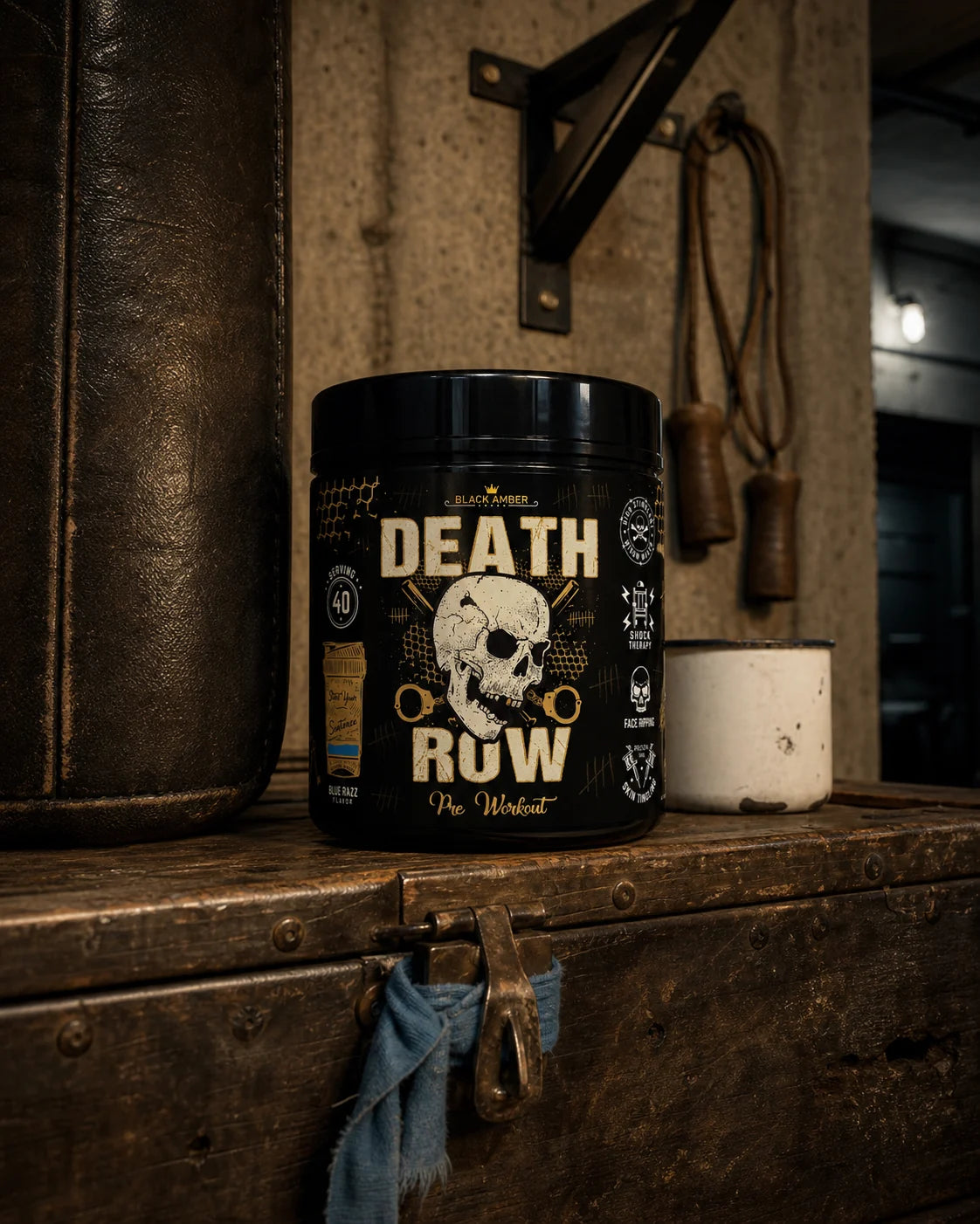 Black Amber Death Row Blue Razz tub on a worn boxing trunk beside a heavy bag