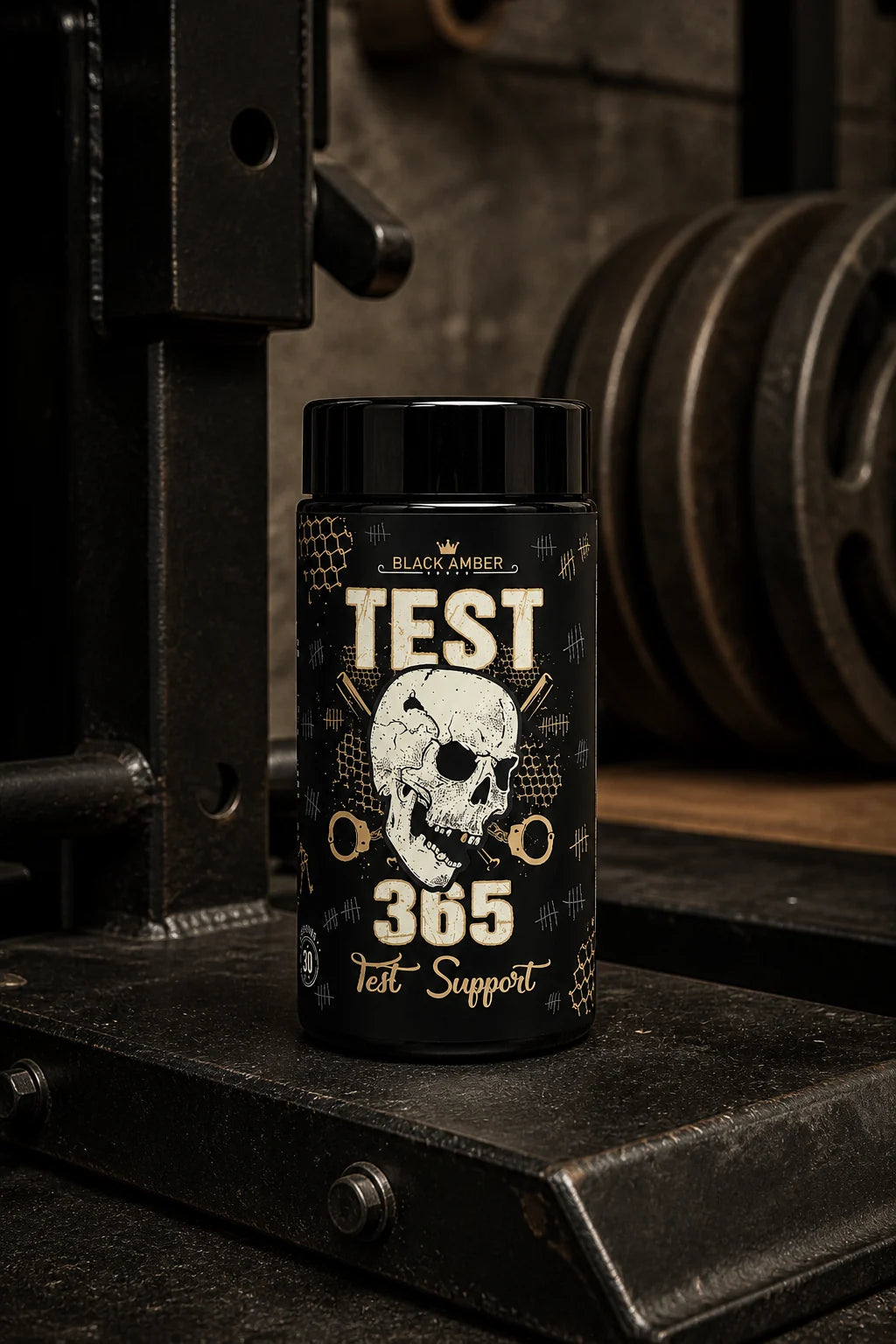 Whole Black Amber Test 365 bottle on a worn steel deadlift-jack platform beside weight plates